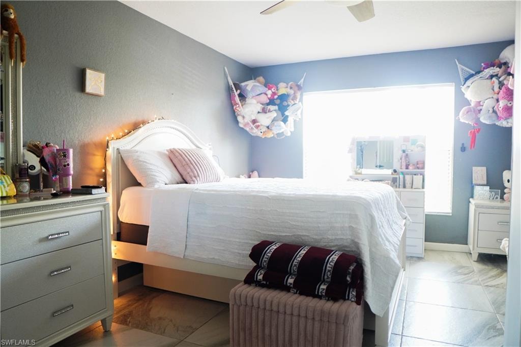 Bedroom featuring ceiling fan and marble finish floors