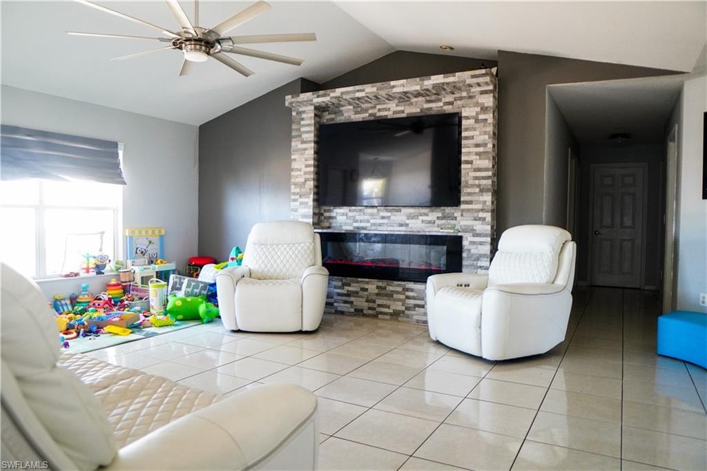 Tiled living room featuring ceiling fan and a glass covered fireplace