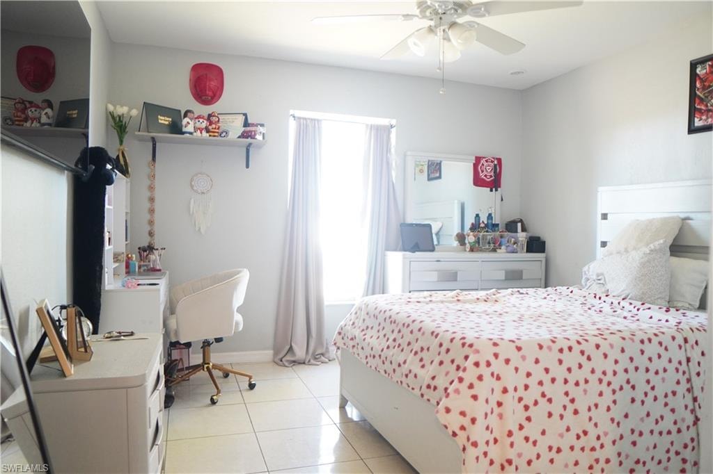 Bedroom with a desk, light tile patterned floors, and a ceiling fan
