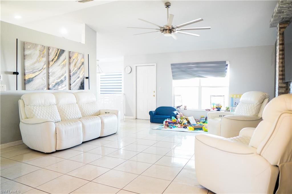 Tiled living area featuring vaulted ceiling and ceiling fan