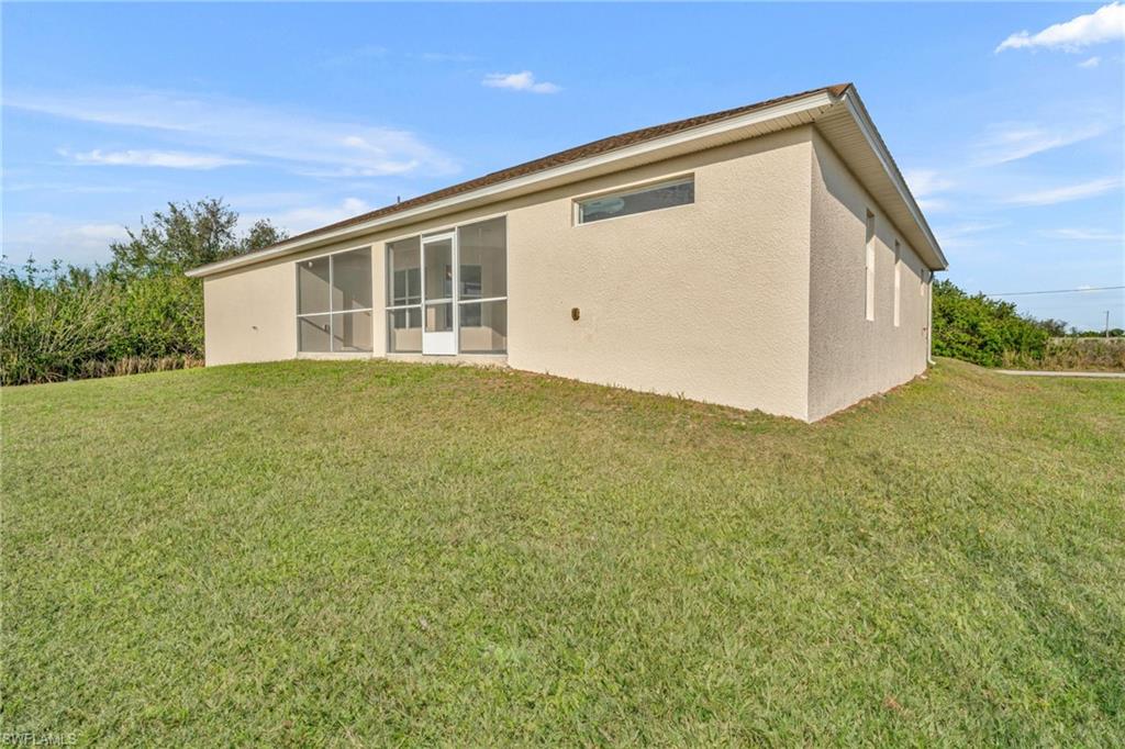 Back of property with stucco siding, a sunroom, and a yard