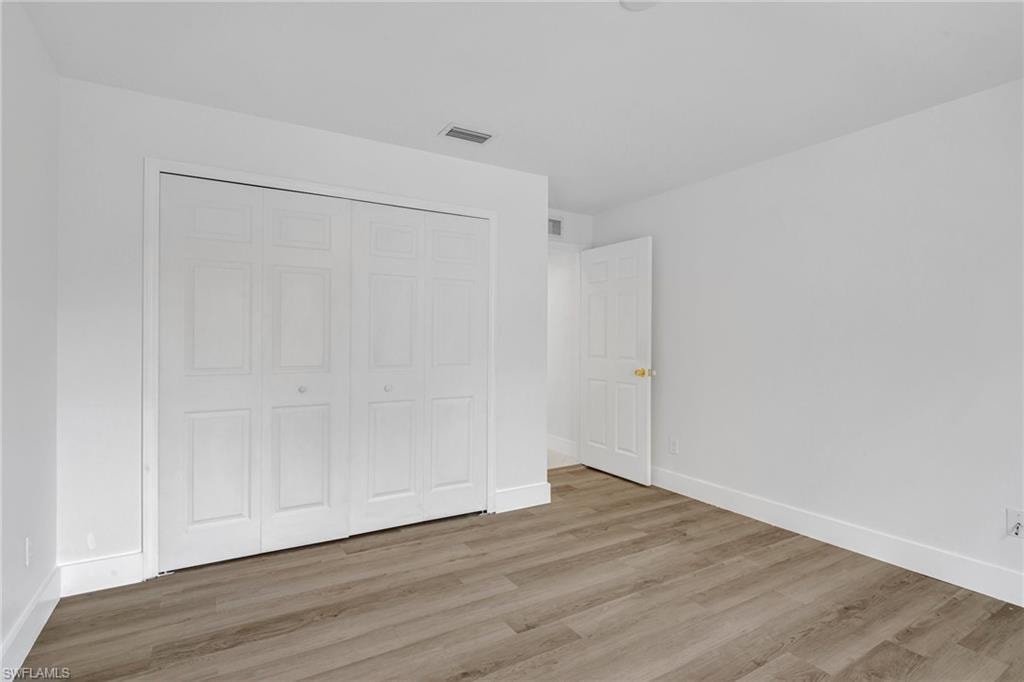 Unfurnished bedroom with wood finished floors and a closet