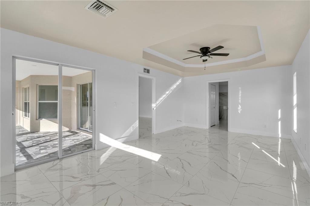 Empty room featuring a raised ceiling and a ceiling fan