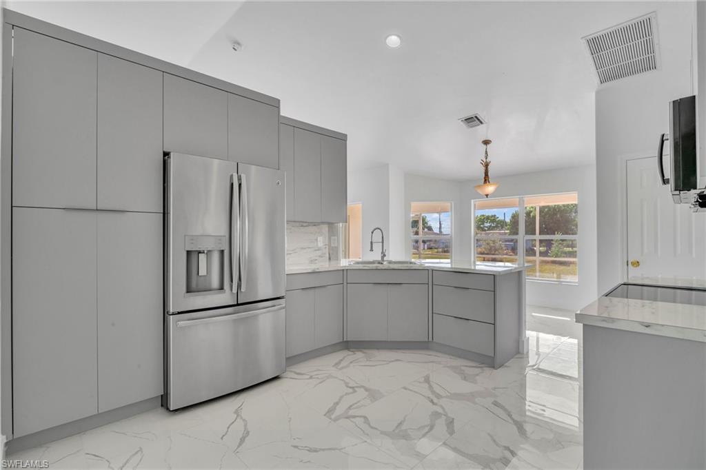 Kitchen featuring light marble finish floors, gray cabinets, stainless steel appliances, a peninsula, and modern cabinets