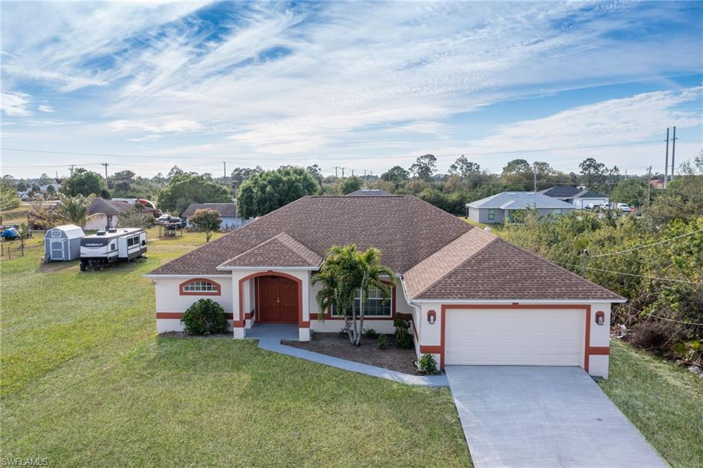 View of front of home with roof with shingles, a front lawn, stucco siding, concrete driveway, and a garage