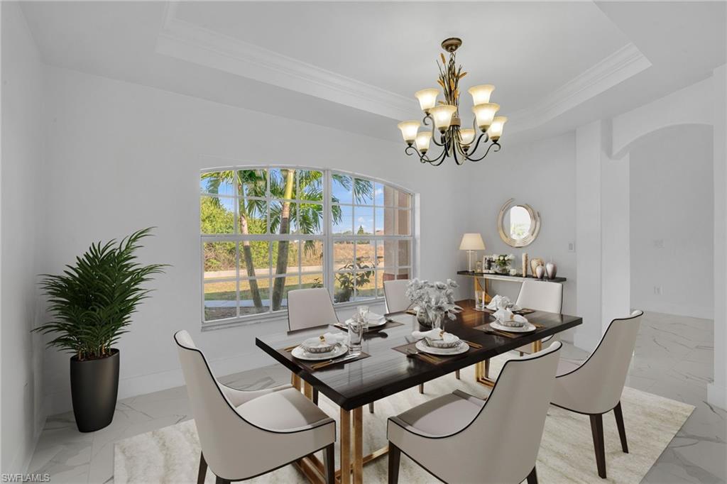 Dining space featuring a tray ceiling, crown molding, a chandelier, light marble finish flooring, and arched walkways