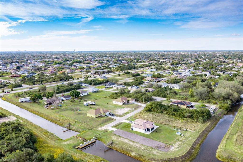 Aerial view of property and surrounding area featuring a nearby body of water and nearby suburban area