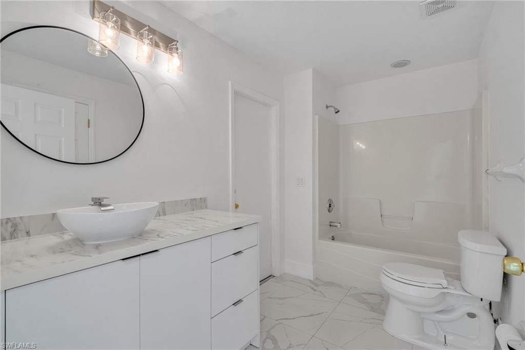 Full bathroom with vanity, shower / bathtub combination, and light marble finish flooring