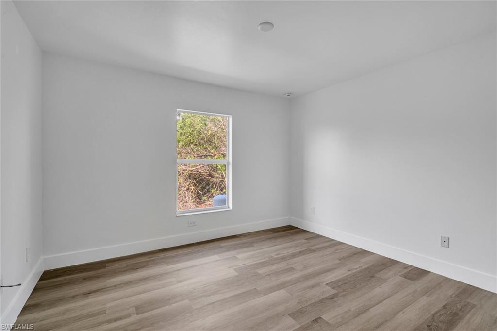 Spare room featuring light wood finished floors and baseboards