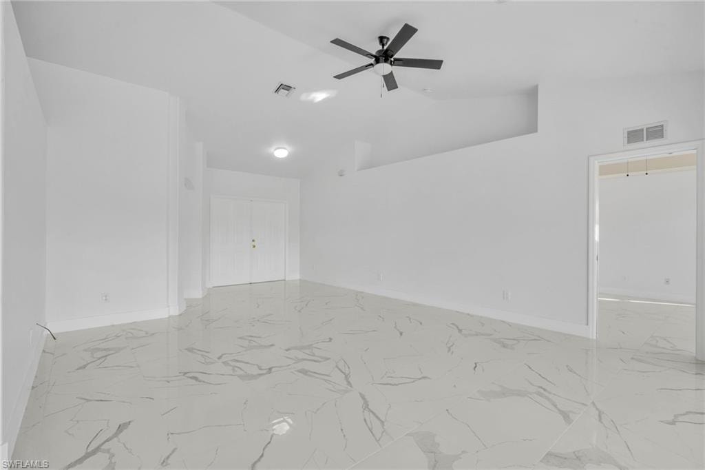 Spare room featuring a ceiling fan, high vaulted ceiling, and light marble finish floors