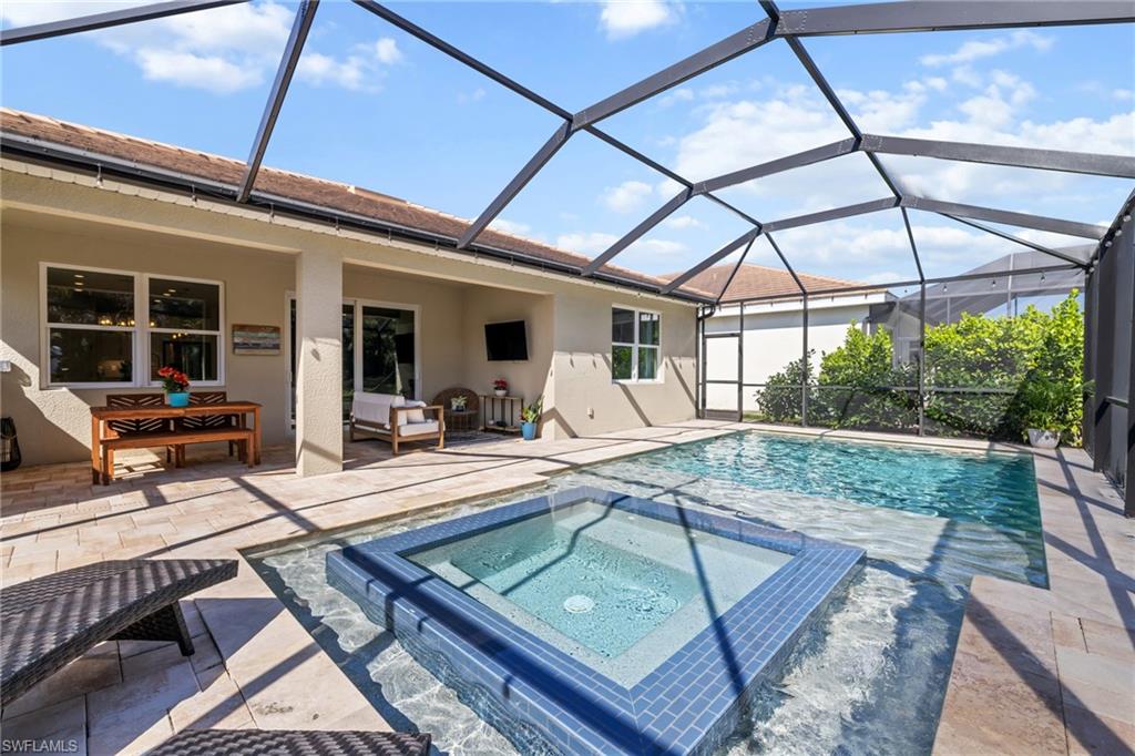 View of swimming pool featuring a sunroom, a patio, glass enclosure, and a pool with connected hot tub