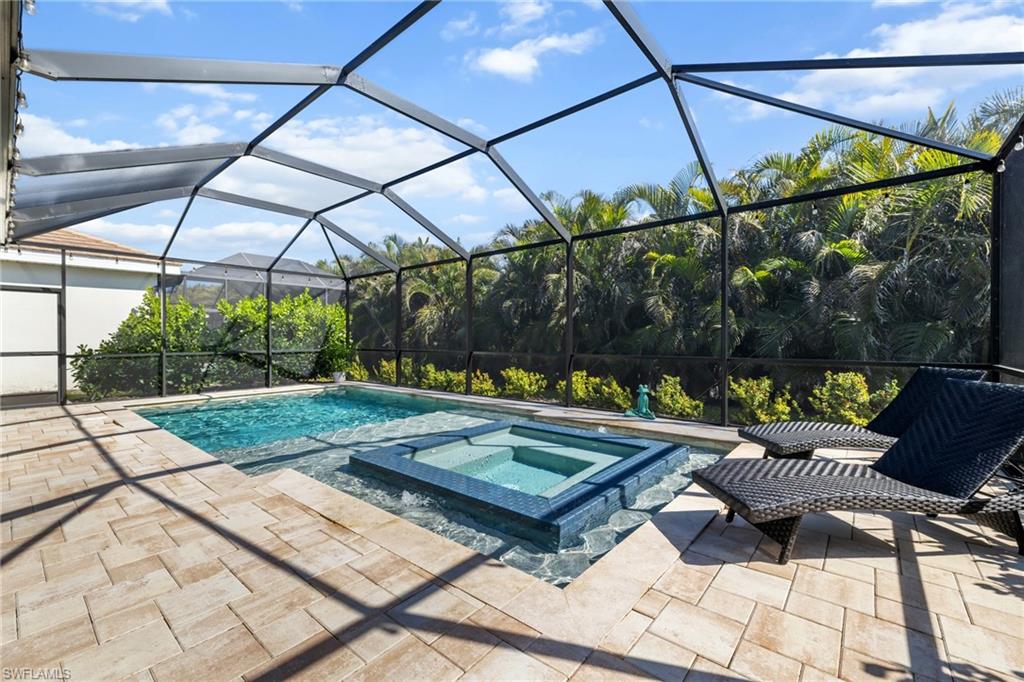 View of pool with a lanai, a sunroom, a pool with connected hot tub, and a patio area