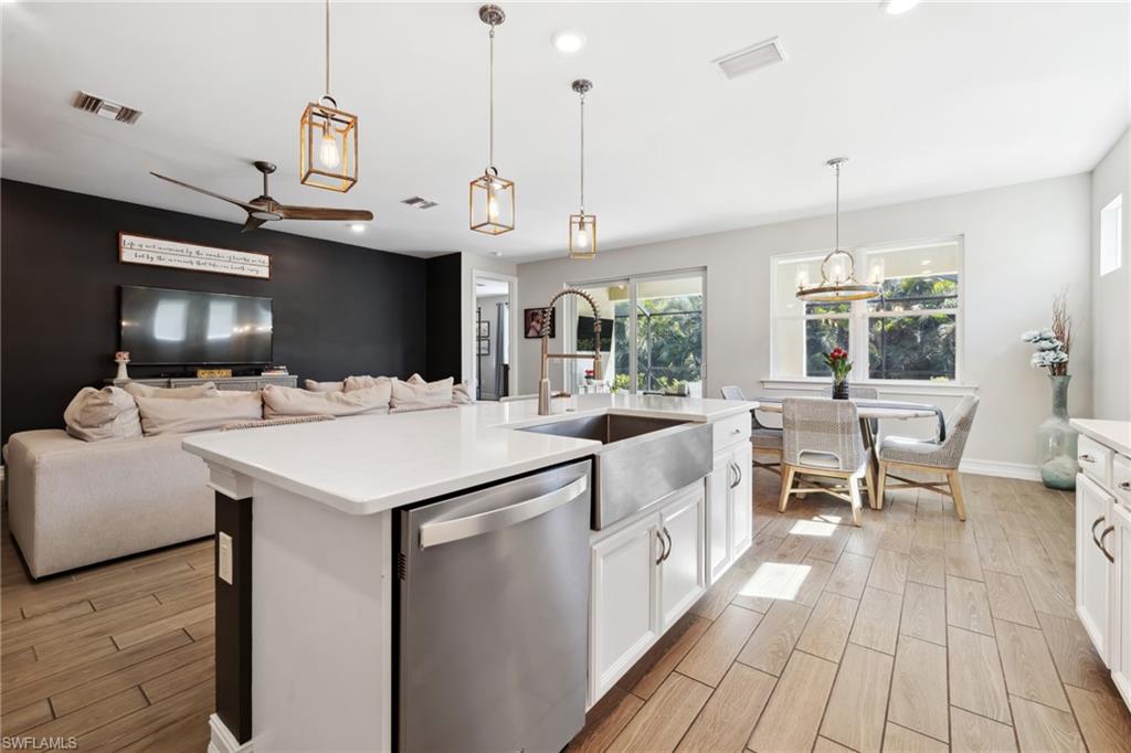 Kitchen with white cabinets, stainless steel dishwasher, wood finish floors, open floor plan, and ceiling fan