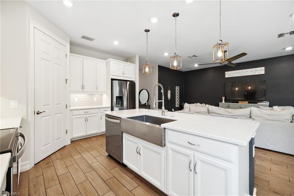 Kitchen featuring hanging light fixtures, white cabinets, appliances with stainless steel finishes, wood finish floors, and recessed lighting