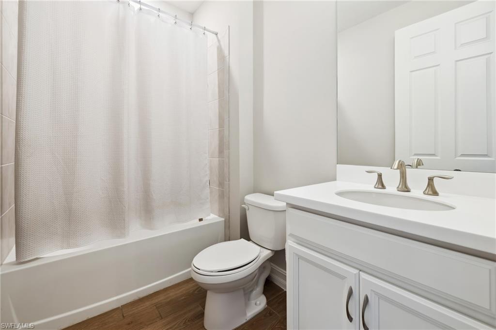 Full bathroom featuring shower / bath combo, vanity, and dark wood-style flooring