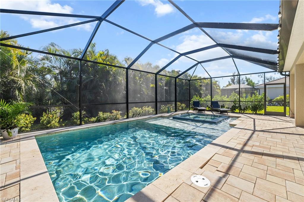 View of swimming pool featuring a sunroom, a lanai, a pool with connected hot tub, and a patio area