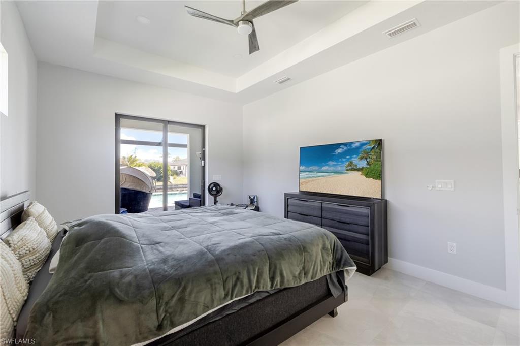 Bedroom with access to exterior, a tray ceiling, and a ceiling fan