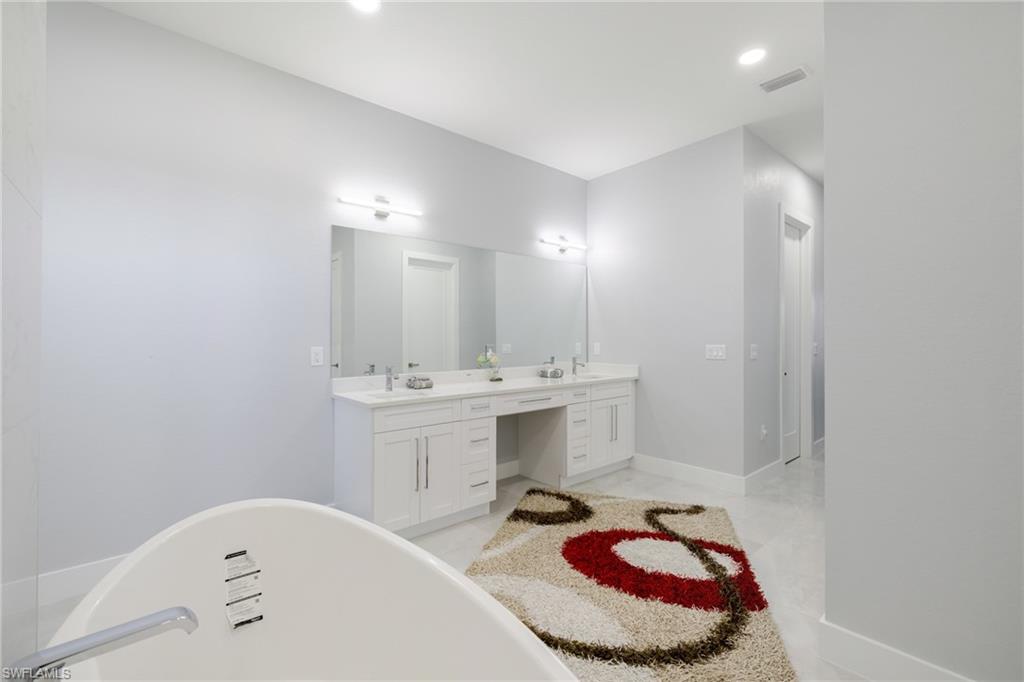 Full bath featuring double vanity, a freestanding tub, and recessed lighting