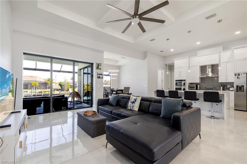 Living room with a tray ceiling, a ceiling fan, a towering ceiling, and recessed lighting