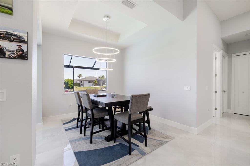 Dining space featuring a raised ceiling and a chandelier