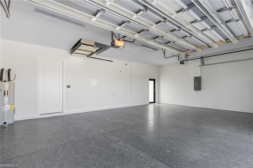 Garage featuring water heater, electric panel, and a garage door opener