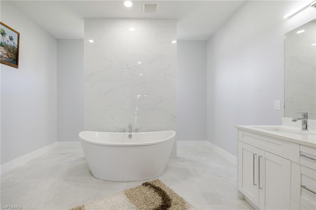 Full bathroom featuring vanity, a freestanding tub, and recessed lighting