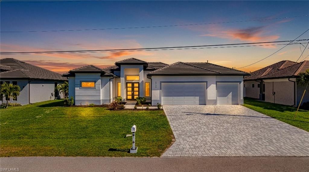 Prairie-style home with a yard, a garage, a tile roof, and stucco siding