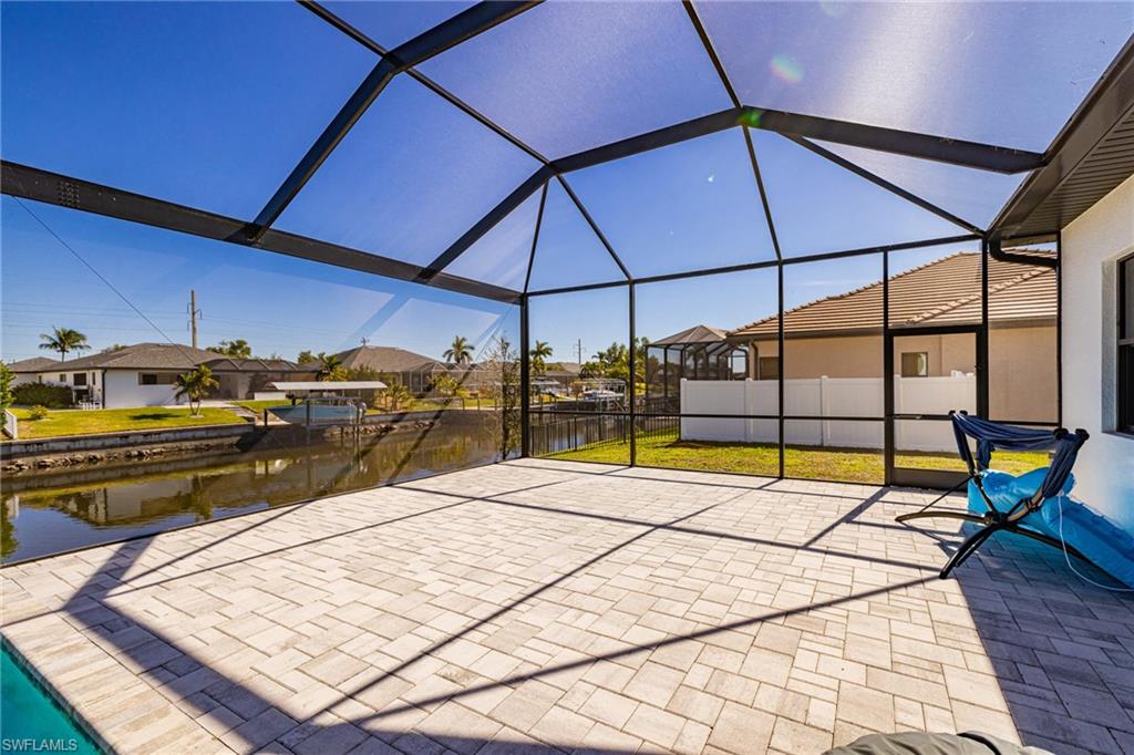 View of patio / terrace featuring a sunroom, a residential view, glass enclosure, and a water view
