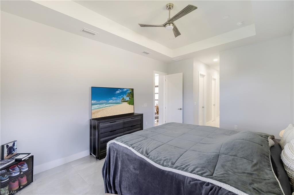 Bedroom featuring a tray ceiling, a ceiling fan, recessed lighting, and light tile patterned flooring