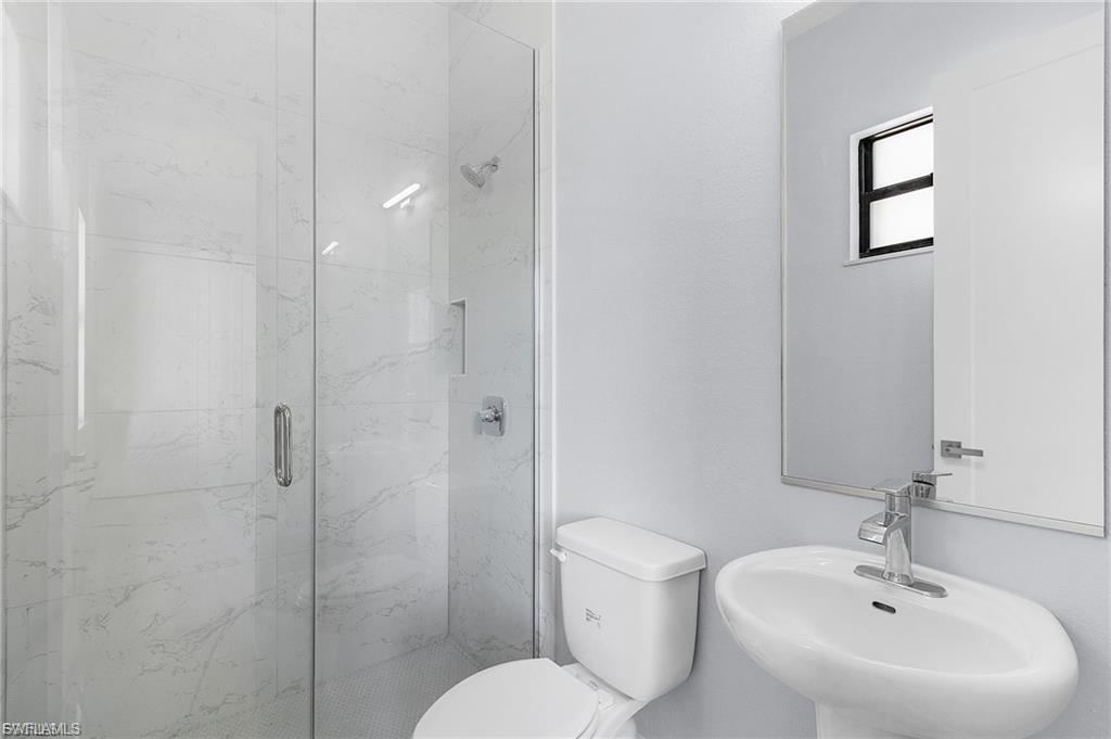 Full bathroom featuring toilet and a marble finish shower