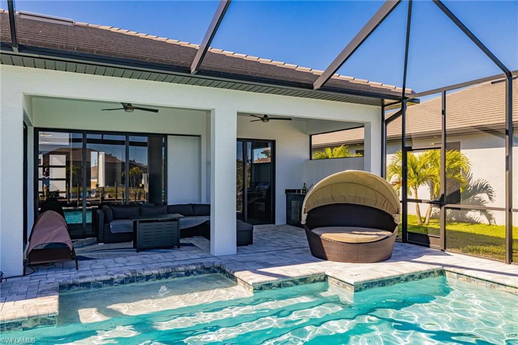 Back of house featuring a lanai, an outdoor pool, and stucco siding