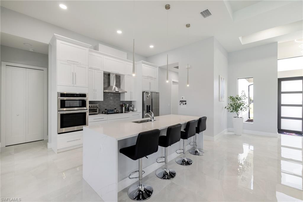 Kitchen featuring a breakfast bar, white cabinets, stainless steel appliances, and pendant lighting