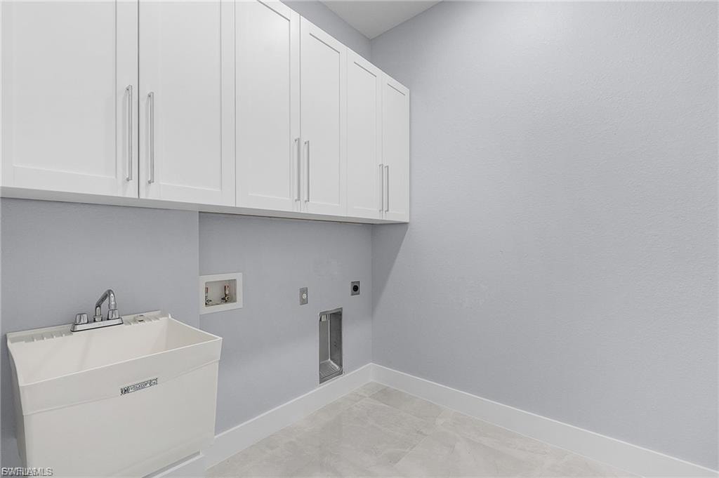 Washroom featuring electric dryer hookup, hookup for a washing machine, and cabinet space