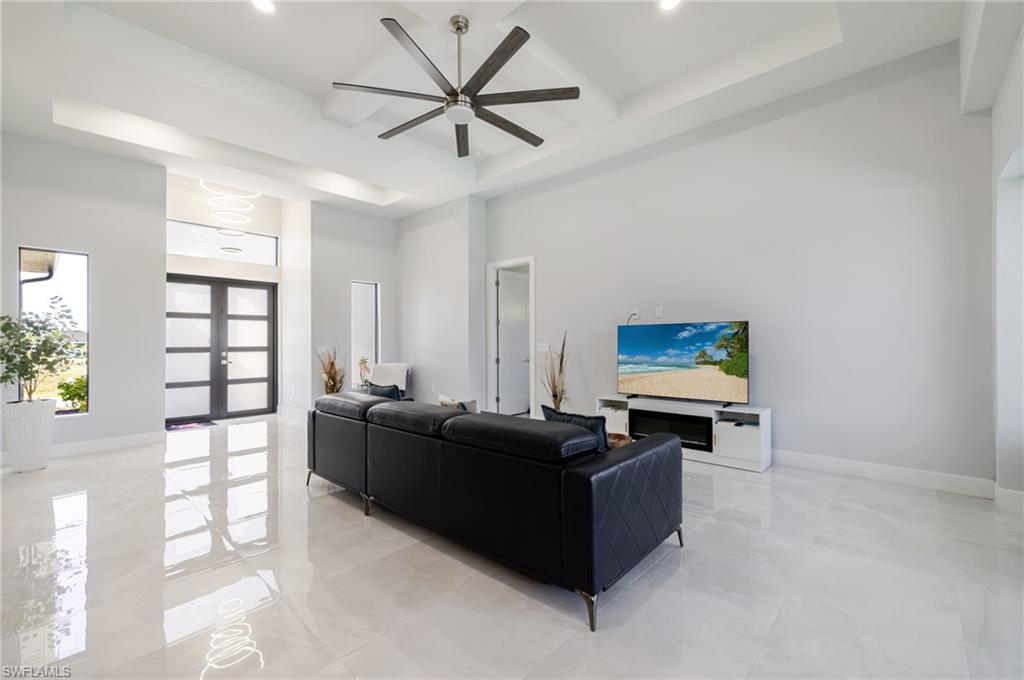 Living area featuring french doors, a towering ceiling, coffered ceiling, a ceiling fan, and a raised ceiling