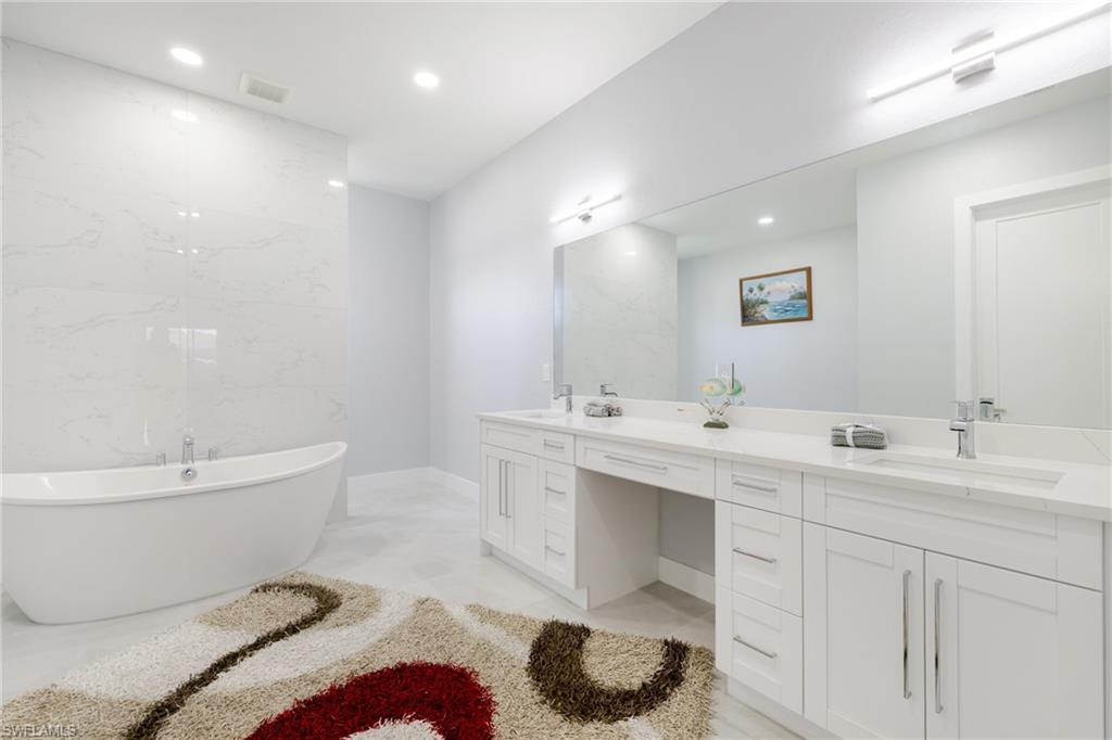 Bathroom with a freestanding tub, double vanity, and recessed lighting