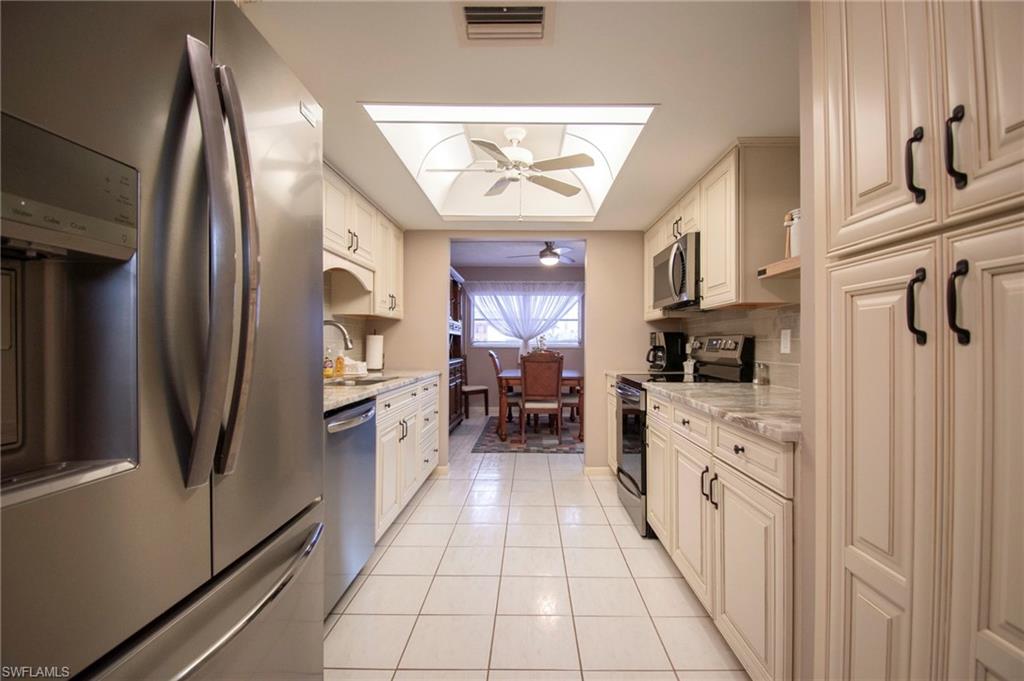 Kitchen featuring stainless steel appliances, light stone countertops, light tile patterned floors, and ceiling fan