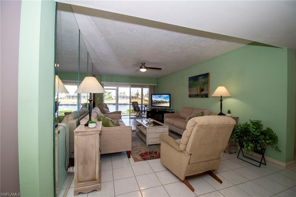 Living area with ceiling fan, a textured ceiling, and light tile patterned floors