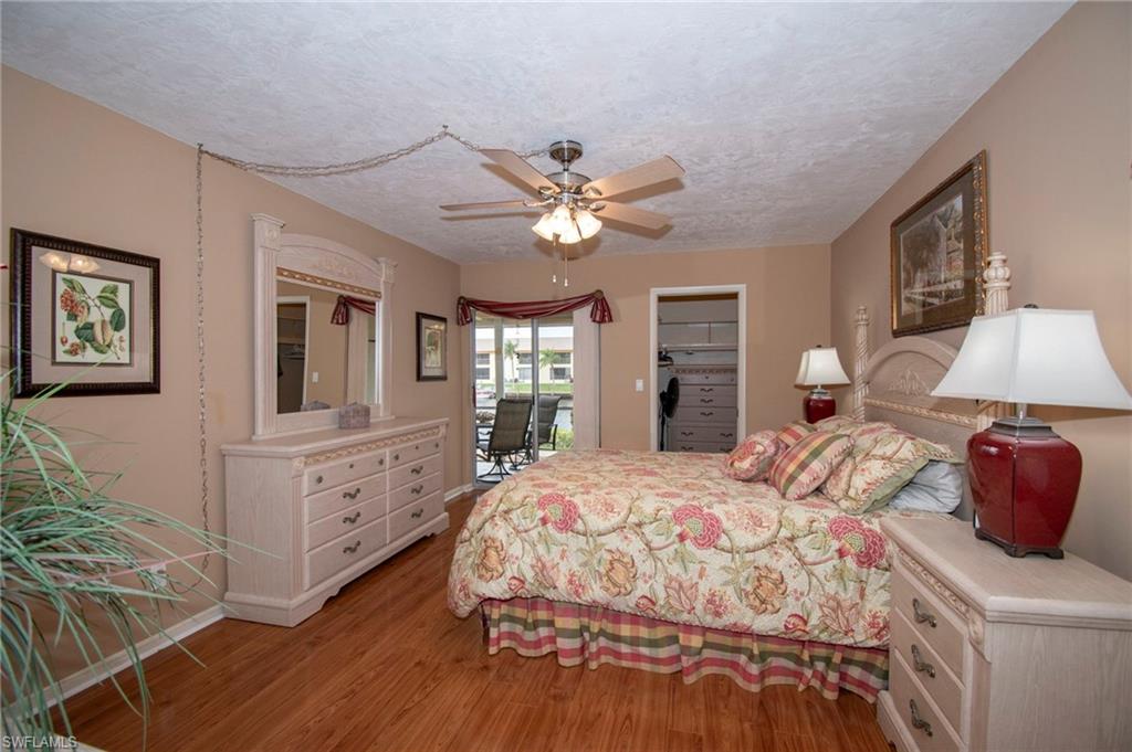 Bedroom featuring access to outside, a spacious closet, light wood-style flooring, a textured ceiling, and ceiling fan