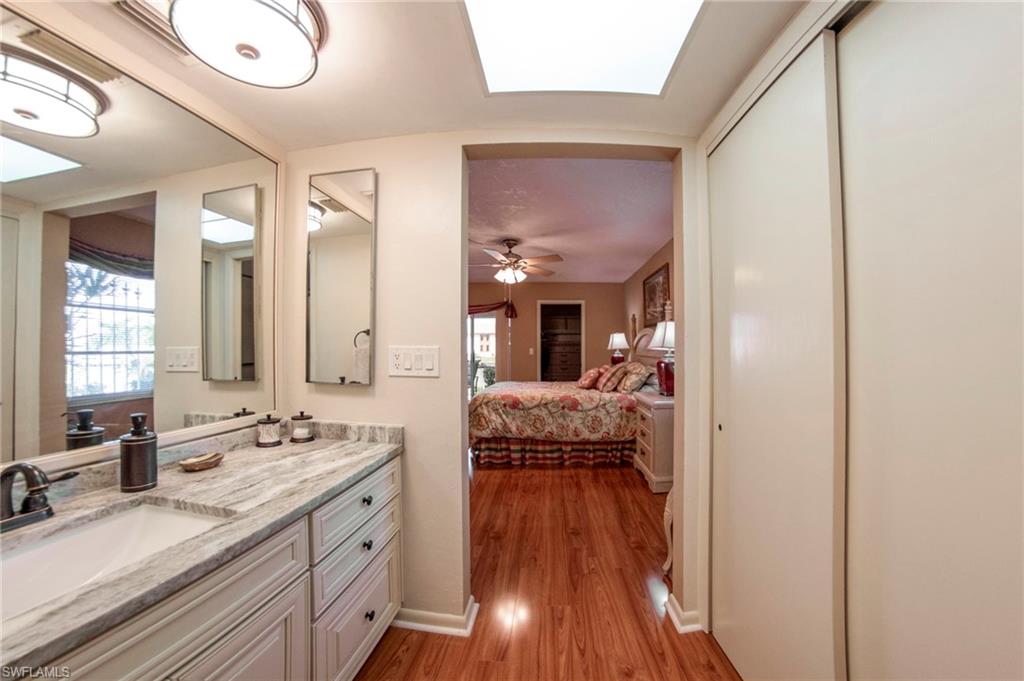 Ensuite bathroom featuring vanity, a skylight, light wood-style flooring, and ceiling fan
