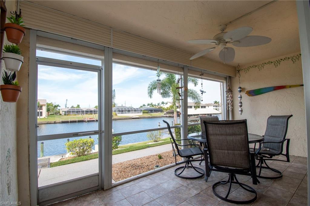Sunroom / solarium with outdoor dining area, a ceiling fan, a water view, and a residential view