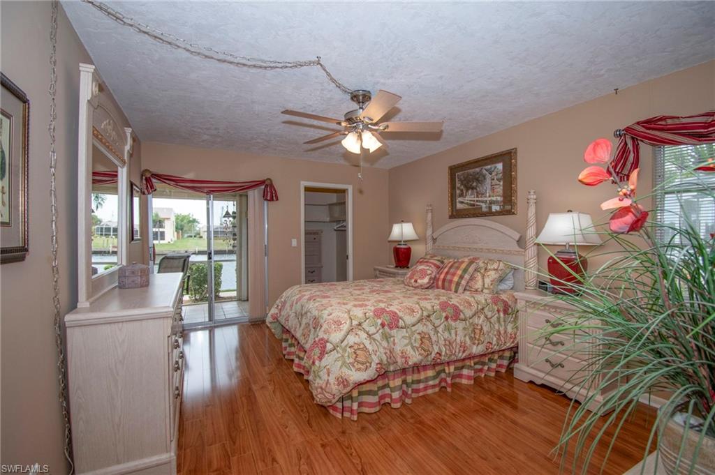 Bedroom with a spacious closet, multiple windows, light wood-type flooring, a textured ceiling, and a ceiling fan