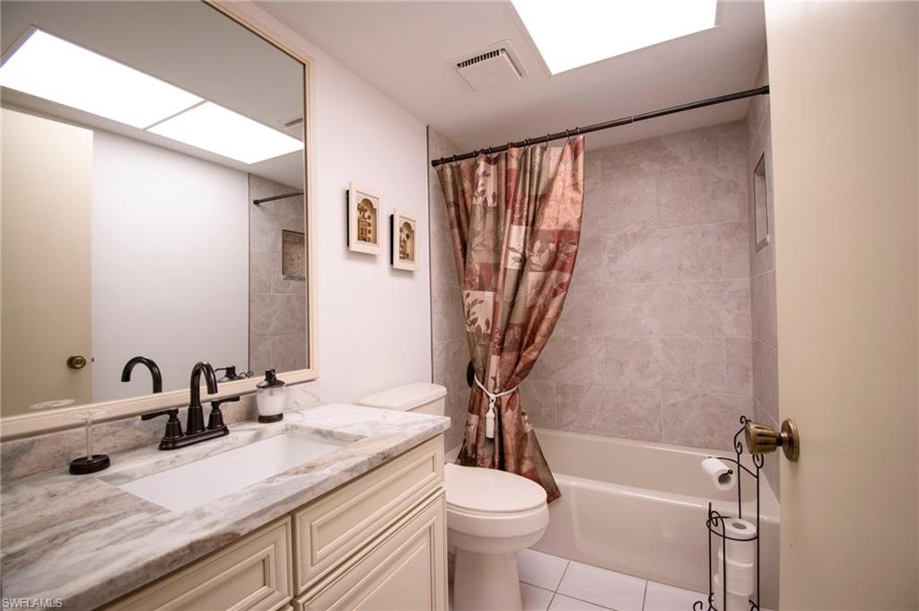 Bathroom featuring shower / bath combo with shower curtain, vanity, and light tile patterned floors