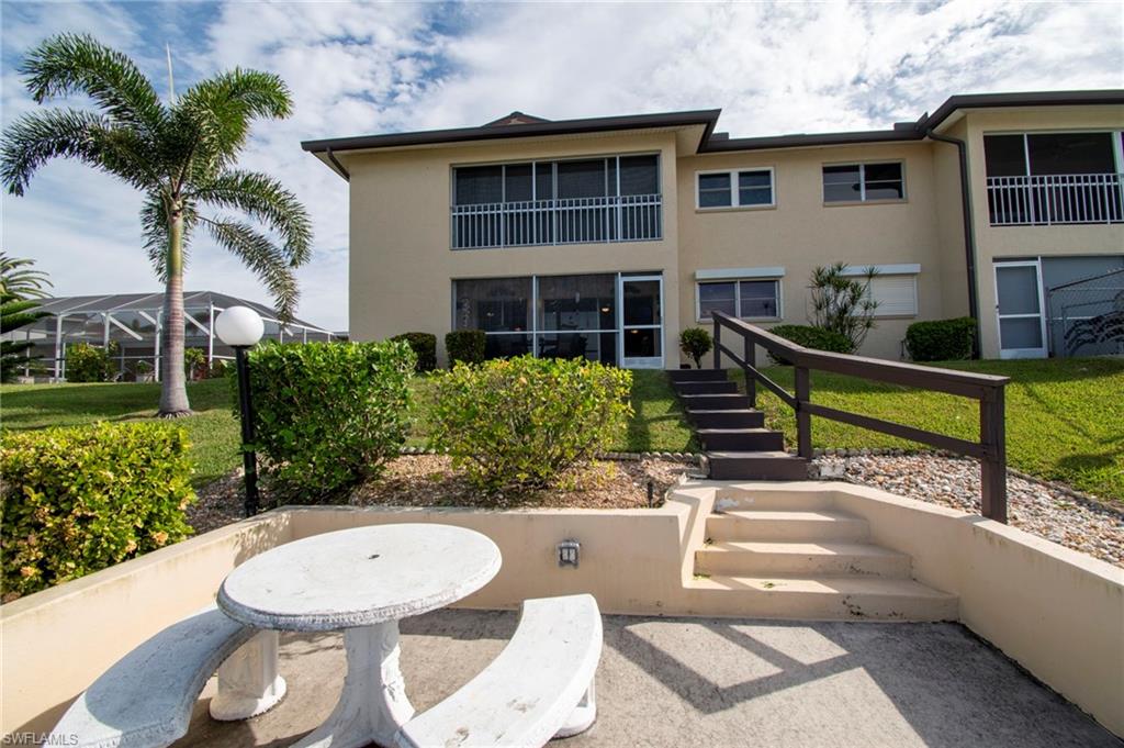 Rear view of property with stucco siding, stairs, a patio area, and a yard