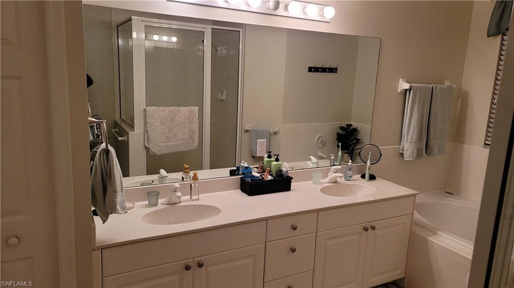 Full bath featuring a garden tub, a stall shower, and double vanity