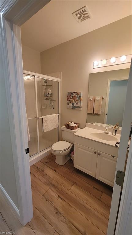 Full bath with vanity, light wood-style flooring, and a shower stall