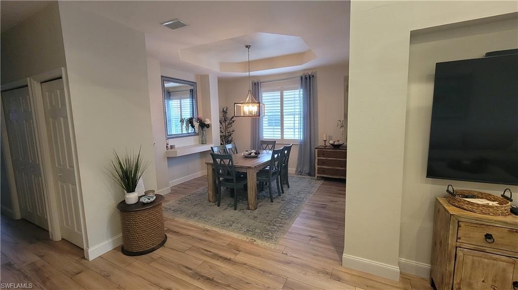 Dining area with a raised ceiling and light wood-style floors