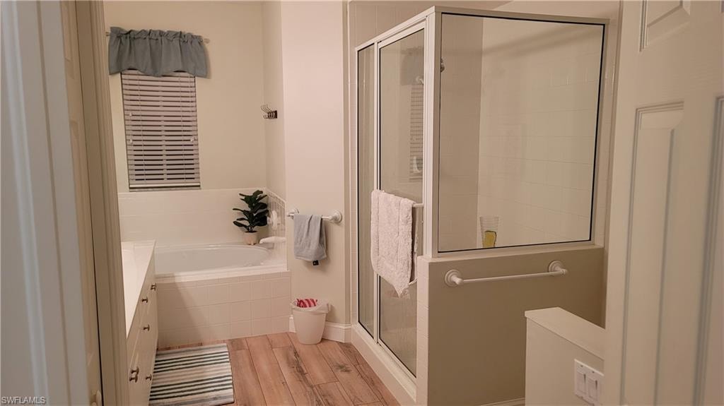 Full bathroom with light wood-style flooring, a stall shower, a bath, and vanity