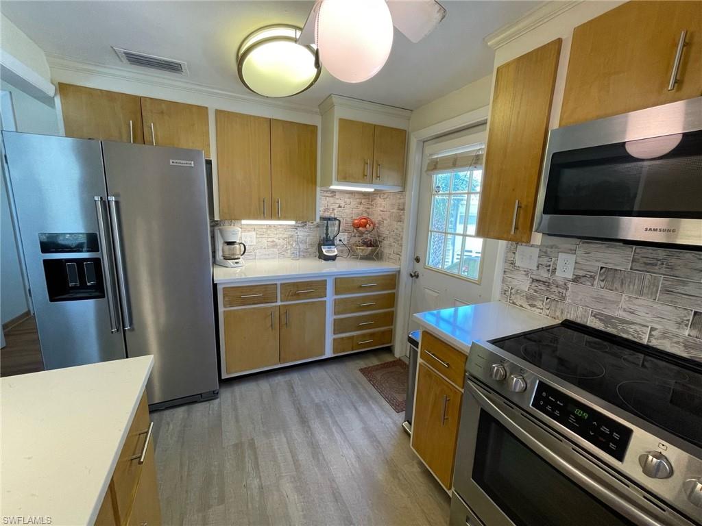 Kitchen with Quartz countertops, visible vents, appliances with stainless steel finishes, and light wood-type flooring