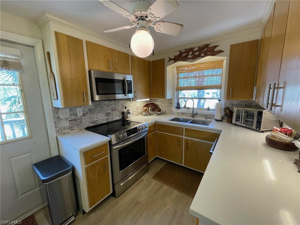 Kitchen featuring a sink, new stainless steel appliances, decorative backsplash, and quartz countertops