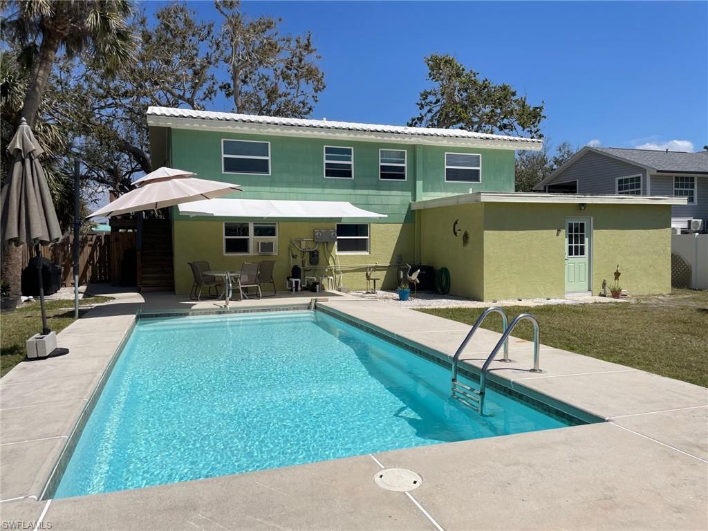 Rear view of house with remote shade awning, and outdoor patio, all fenced
